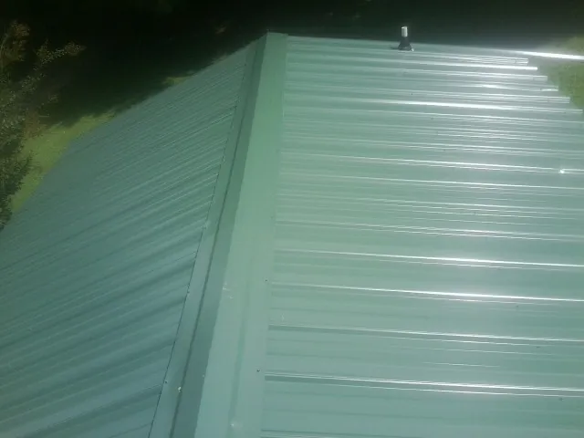 New green metal panels meeting at the ridge of a roof — Flat Roof Repair work by our crew in Albion